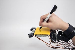 Robo-Hand: hält Block, während User schreibt (Foto: http://fluid.media.mit.edu) Robo-Hand: hält Block, während User schreibt (Foto: http://fluid.media.mit.edu)